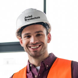 Portraitbild eines Ausbilders mit einem weißen Baustellenhelm