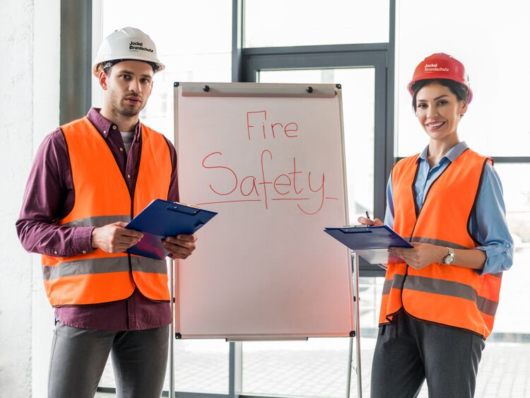 Ausbilder und Ausbilderin stehen an einem Wideboard und erklären das Verhalten im Brandfall